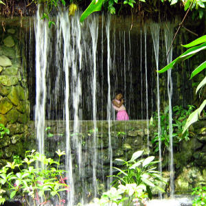 Streaming man-made waterfalls where the girl posing behind the water curtain.